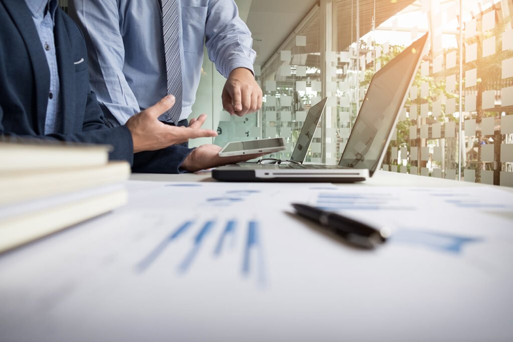 Profissionais em reunião analisando relatórios da empresa no notebook