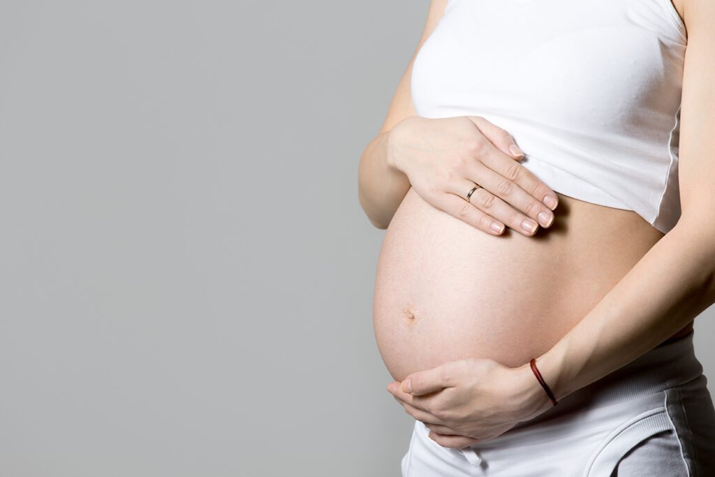 Candidata gestante com as mãos sobre a barriga: remarcação do teste de aptidão física em concurso público